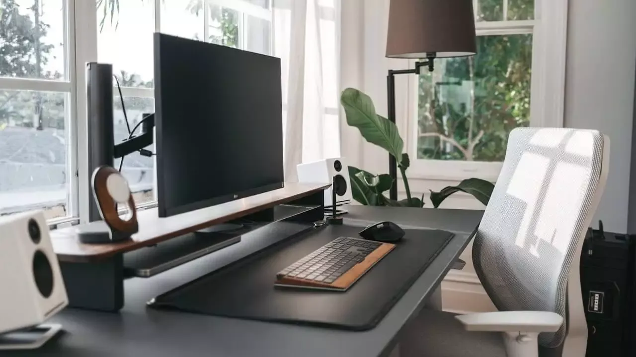 Home office desk with a monitor, keyboard and ergonomic chair